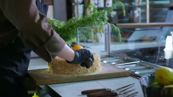 Bakeries, a Professional Female Chef in Gloves Cut Freshly Baked Dessert Cake with Knife on Cutting