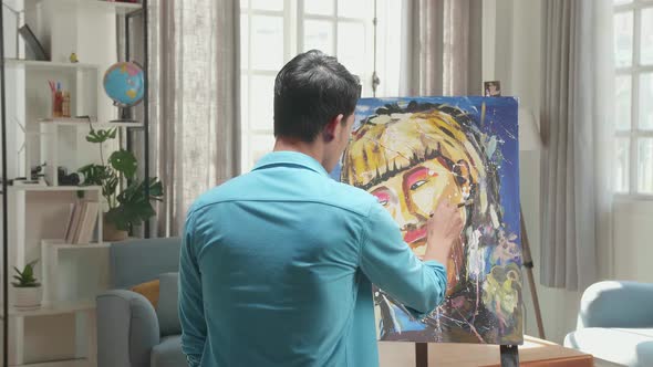 Asian Artist Man Holding Paintbrush Mixed Colour And Painting A Girl's Hair On The Canvas