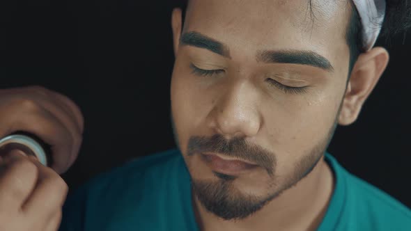 Close up of man's face and make up artist's hands with make up brush putting a face powder