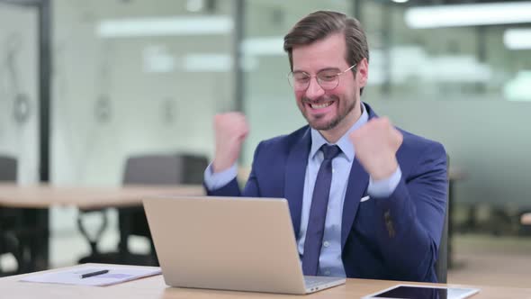 Excited Young Businessman Celebrating Success on Laptop 