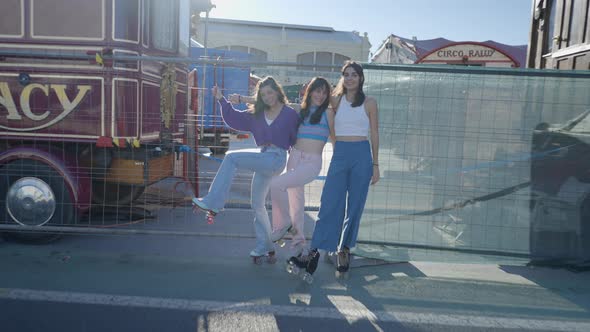 Pushin of Three Happy Girls in Roller Skates Standing By Metal Fence