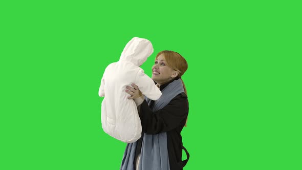 Happy Loving Mother Playing with Her Baby Outside in Autumn on a Green Screen, Chroma Key.