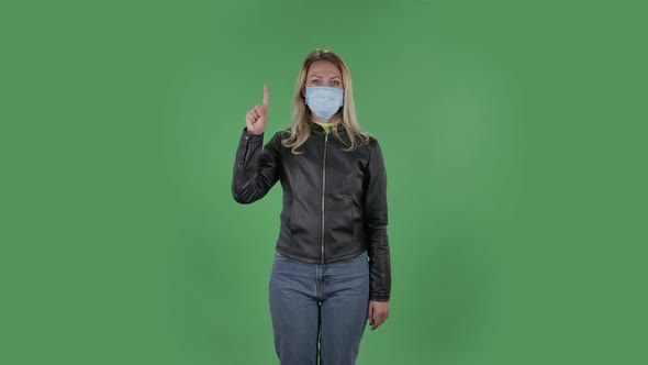 Portrait of Beautiful Young Woman in Medical Protective Face Mask Is Looking at Camera and Shows
