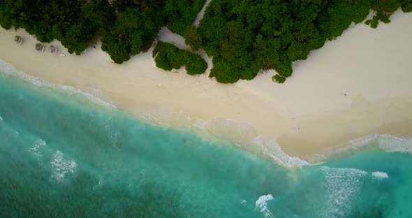 Tropical above island view of a sandy white paradise beach and blue ocean background in colourful 4K