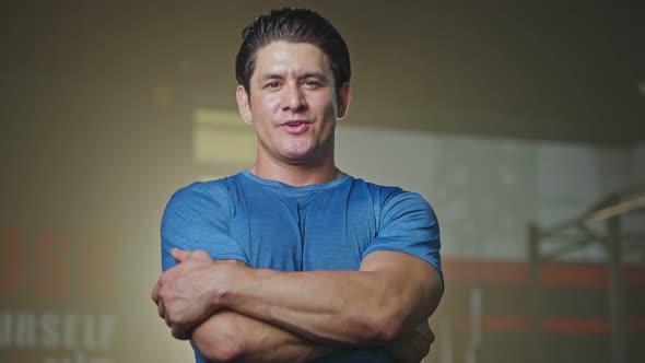 Close-up of Caucasian young male athlete or sportsman standing in the dark of training gym stadium.