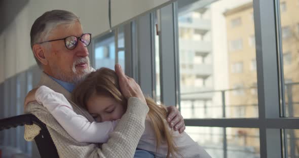 Preteen Girl Hugging Grandfather in Wheelchair Visiting at Hospital