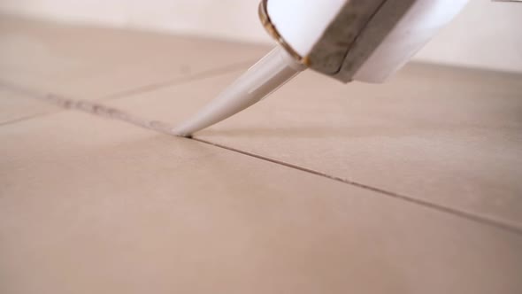 Closeup Image of Applying Silicone Sealant with a Sealing Gun Silicone Glue to Ceramic Tiles in the