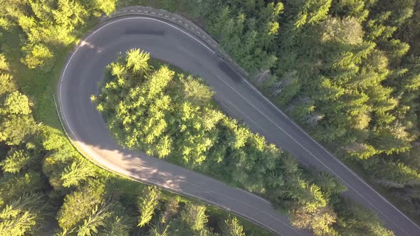 Aerial view of winding road in high mountain pass trough dense woods.