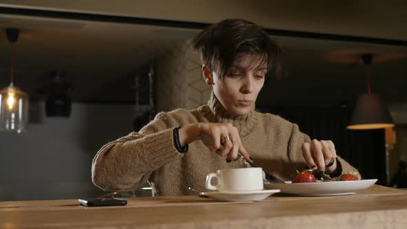 a Lonely Woman Eats Salad Sitting at the Bar in a Restaurant