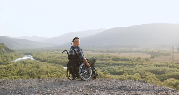 Side View of Handsome Confident Disabled Young Man in Wheelchair Which Walking on the Hill To See