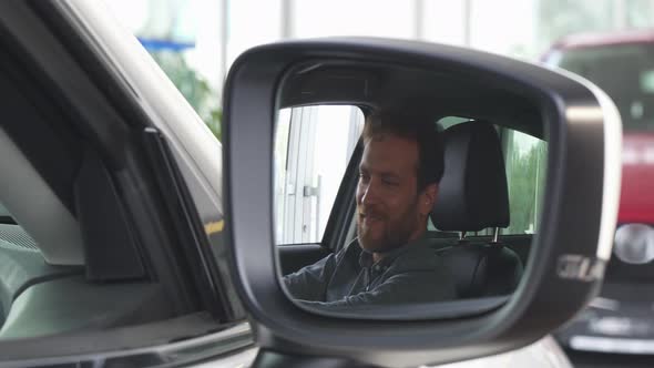 Selective Focua on a Side Mirror of a Car, Happy Man Relaxing in a New Auto