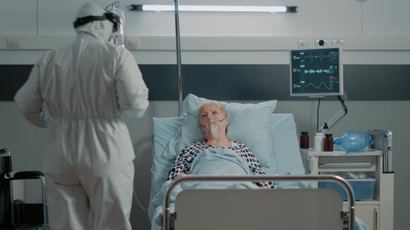 Doctor with Hazmat Suit Doing Checkup Visit for Aged Woman