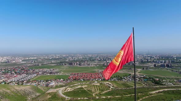 Aerial view of Bishkek city from the mountains. Flagpole with Kyrgyzstan flag