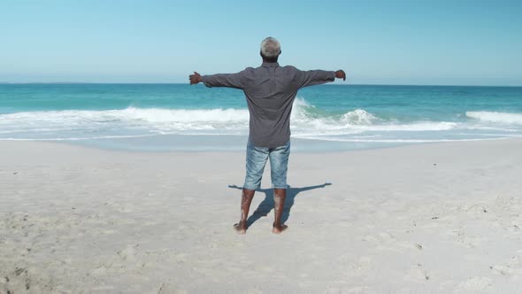 Senior man raising his arms at the beach