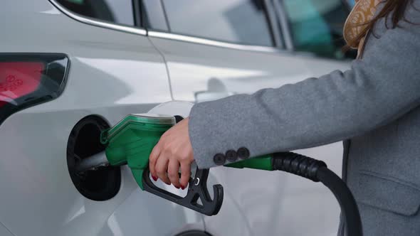 Woman Fills Petrol Into Her Car at a Gas Station Closeup