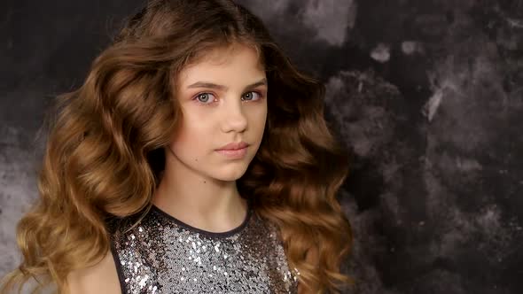 Portrait of a schoolgirl girl on a gray background. A beautiful child