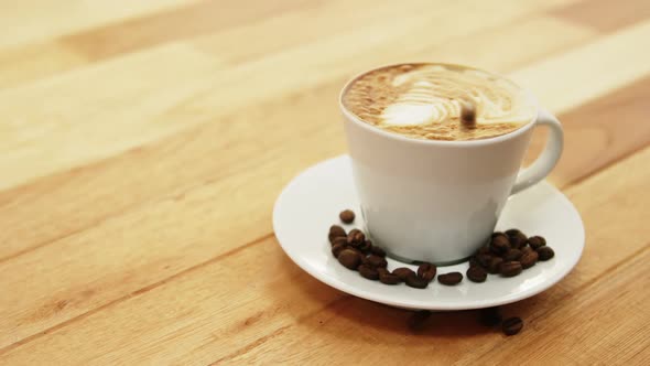 Close-up of coffee cup with saucer and coffee beans