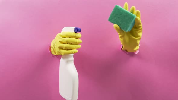Hands in Rubber Yellow Gloves Holding a Sponge and Spray for Washing Windows
