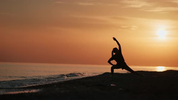 Athletic Female Doing Yoga Exercise Stretching Body at Sunset Beach