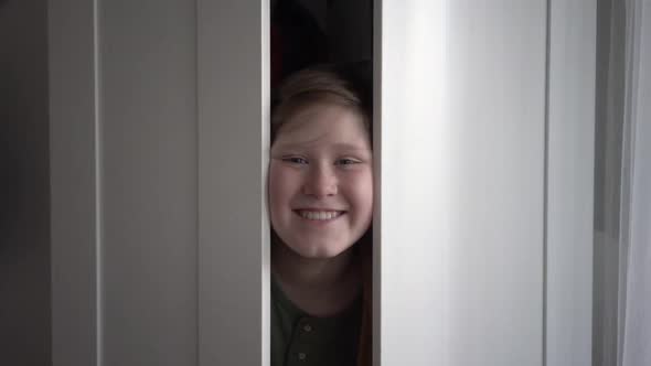 Boy playing hide and seek, opening in a wardrobe at home