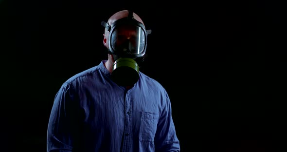 Portrait of a Man in a Blue Shirt and White Protective Gloves on a Black Background. He Adjusts the