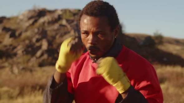 Black Man with Bandaged Fists Boxing Outdoors Training Punches Front View