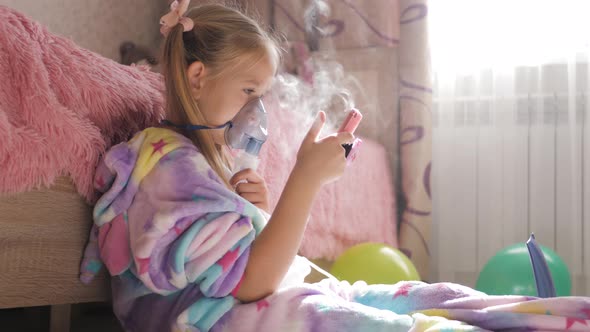 Little Girl Holds Inhaler Mask at Home. Sick Kid Breathes Through a Nebulizer. Baby Using Equipment