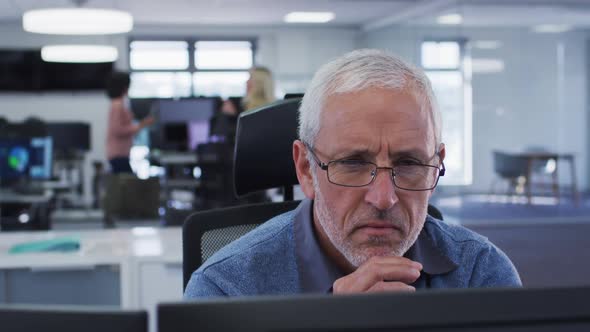 Thoughtful man looking at his computer screen while sitting on his desk at office