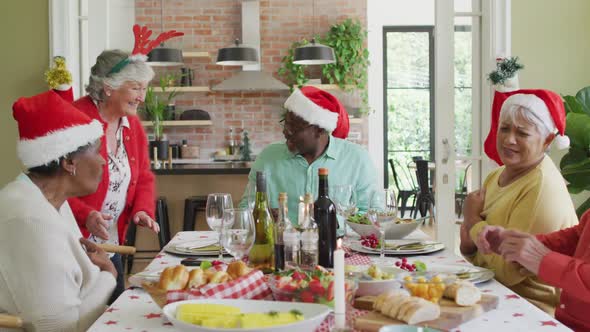 Happy group of diverse senior friends celebrating meal at christmas time