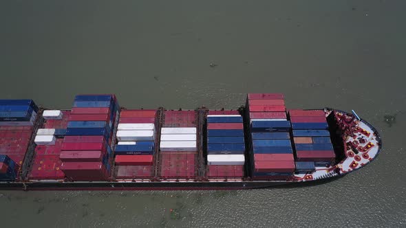 Aerial side and top view of a large container ship cruising slowly along on a sunny day.