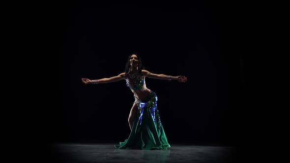 Attractive Girl Performing a Belly Dance. Black Background