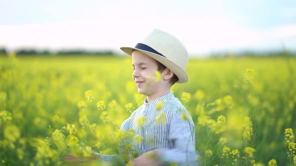 Little Boy in a Hat in Yellow Field of Rapeseed.