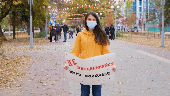 A Woman Raises a Poster with Russian Text Translation From Russian Do Not Vaccinate Die Young