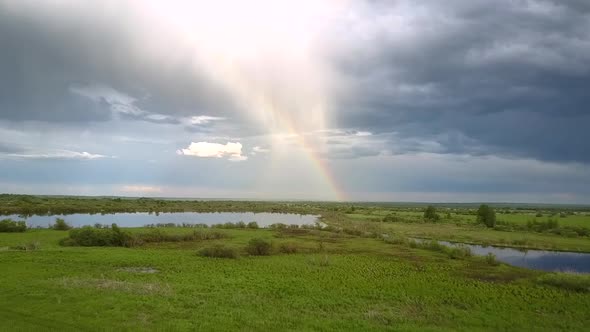 Wide Calm River Reflects Colourful Rainbow and White Clouds