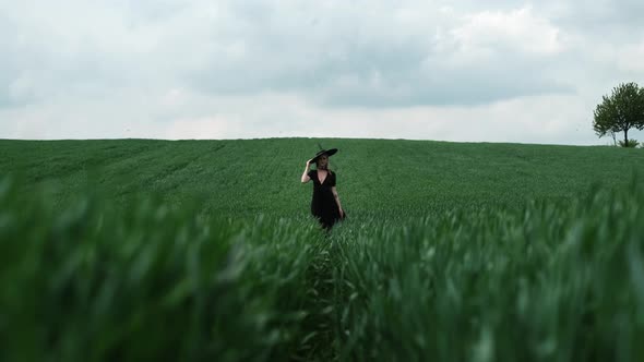 Girl In Black Big Hat Stands Alone In The Middle Of The Field.