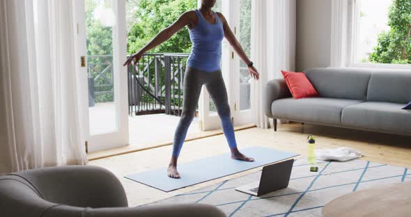 African american woman performing stretching exercise at home