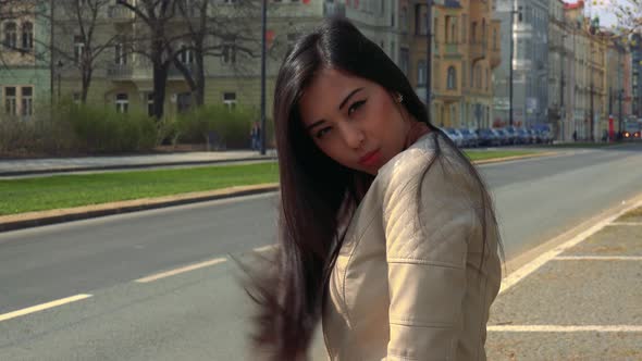 A Young Asian Woman Poses for the Camera in a Street in an Urban Area