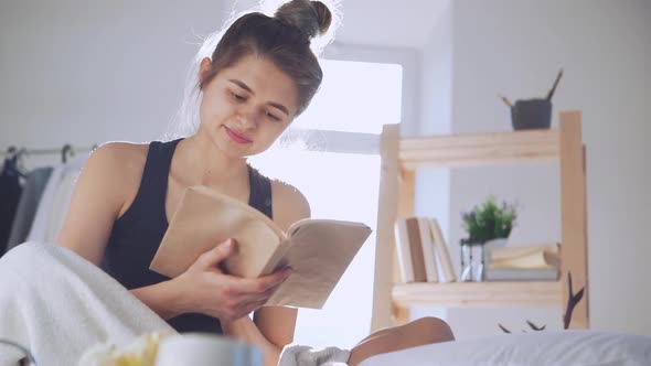 Young Caucasian Lady Reading Book in Bed in Slowmotion