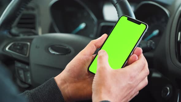 Driver Using a Smartphone Inside the Car. Chromakey Smartphone with Green Screen. Auto Navigation