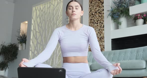 Young Woman Meditating Using Tablet Mobile App for Breathing and Meditation