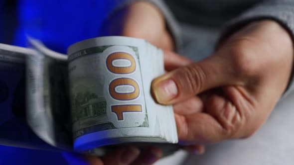 Hands Checks US Dollar Bills or Counting in Cash Against the Backdrop of Police Car Lights