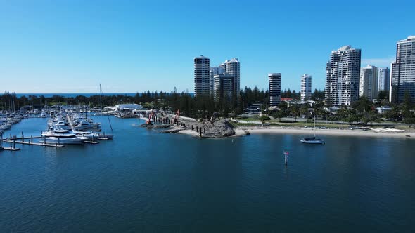 Coastal construction project in a boating marina and harbor next to a towering city skyline. Moving