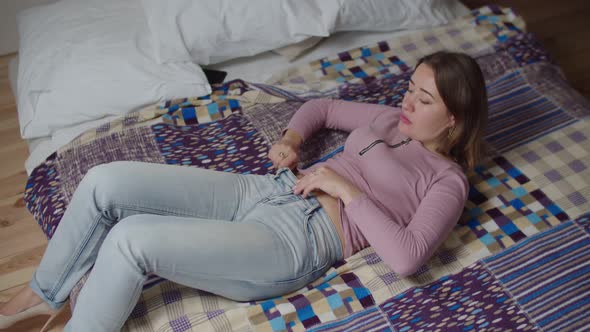 Top View of Frustrated Charming Female Trying to Squeeze Into Tight Jeans After Gaining Weight