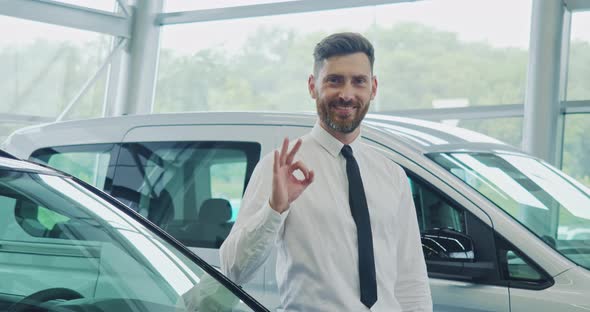 Man Smiling and Gesturing While Standing at Auto Salon