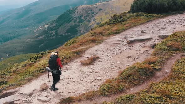 Aerial View of a Traveler Photographer with Backpack Climbing By Mountain Range