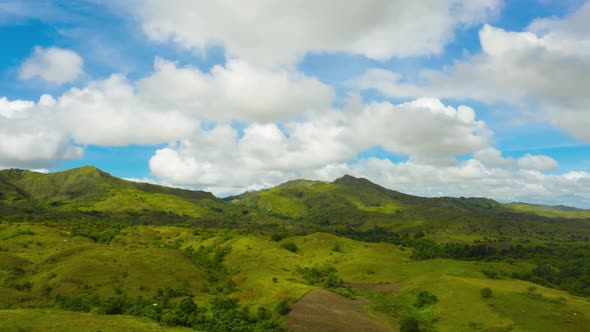 Hills with Green Grass and Blue Sky with White Puffy Clouds