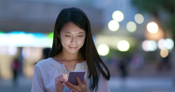 Woman use of mobile phone in the city at night