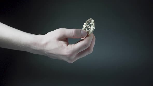 Throwing Bitcoin coins up in air and catching them, black background.