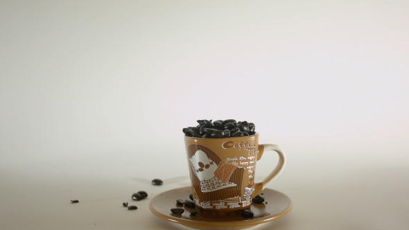 Coffee Beans Poured Into Small Coffee Cup