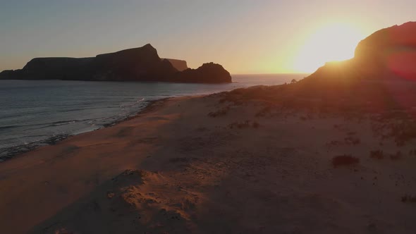 Aerial backwards shot, Calheta beach sunset lights, islet as background